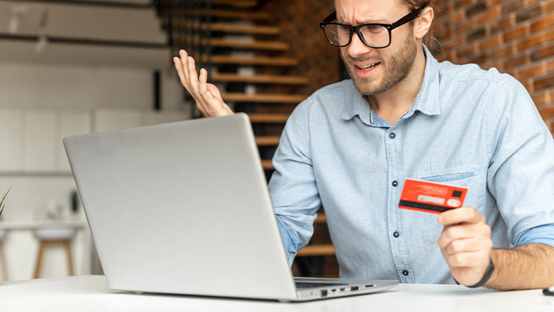 uomo davanti a PC con carta di credito in mano